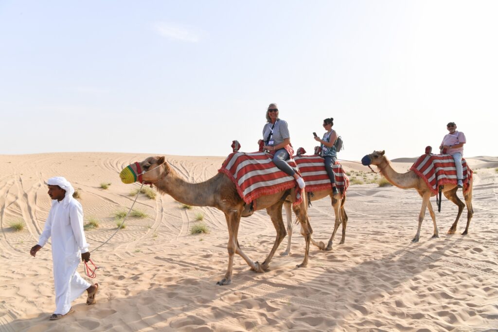 Conference attendees ride camels through the desert