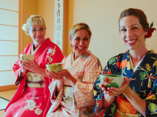 Three women in kimonos holding Bonsai plants