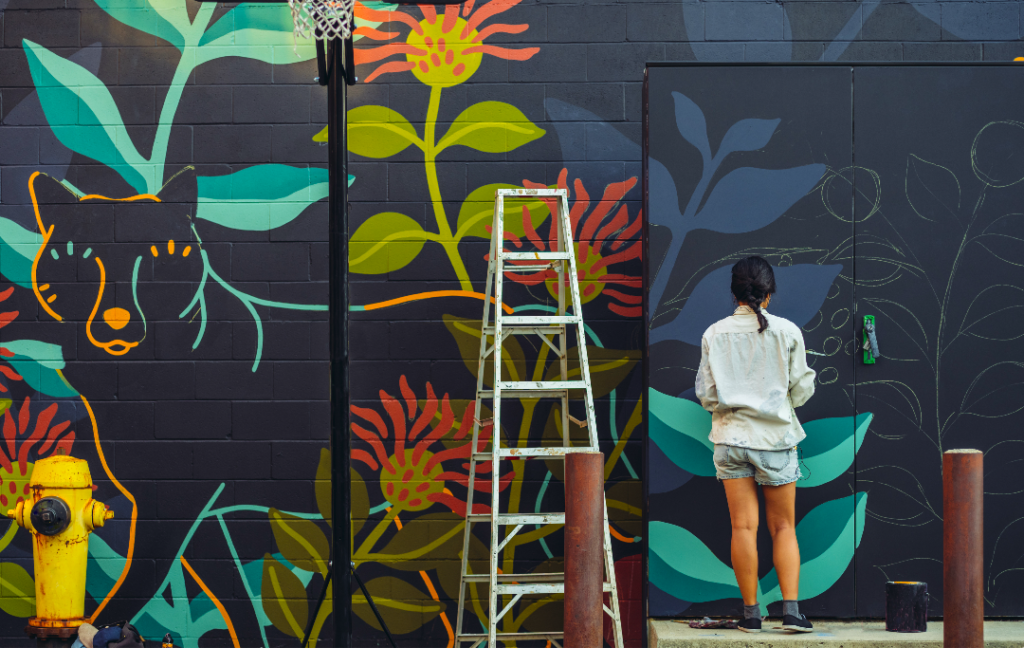 woman painting mural of a jaguar