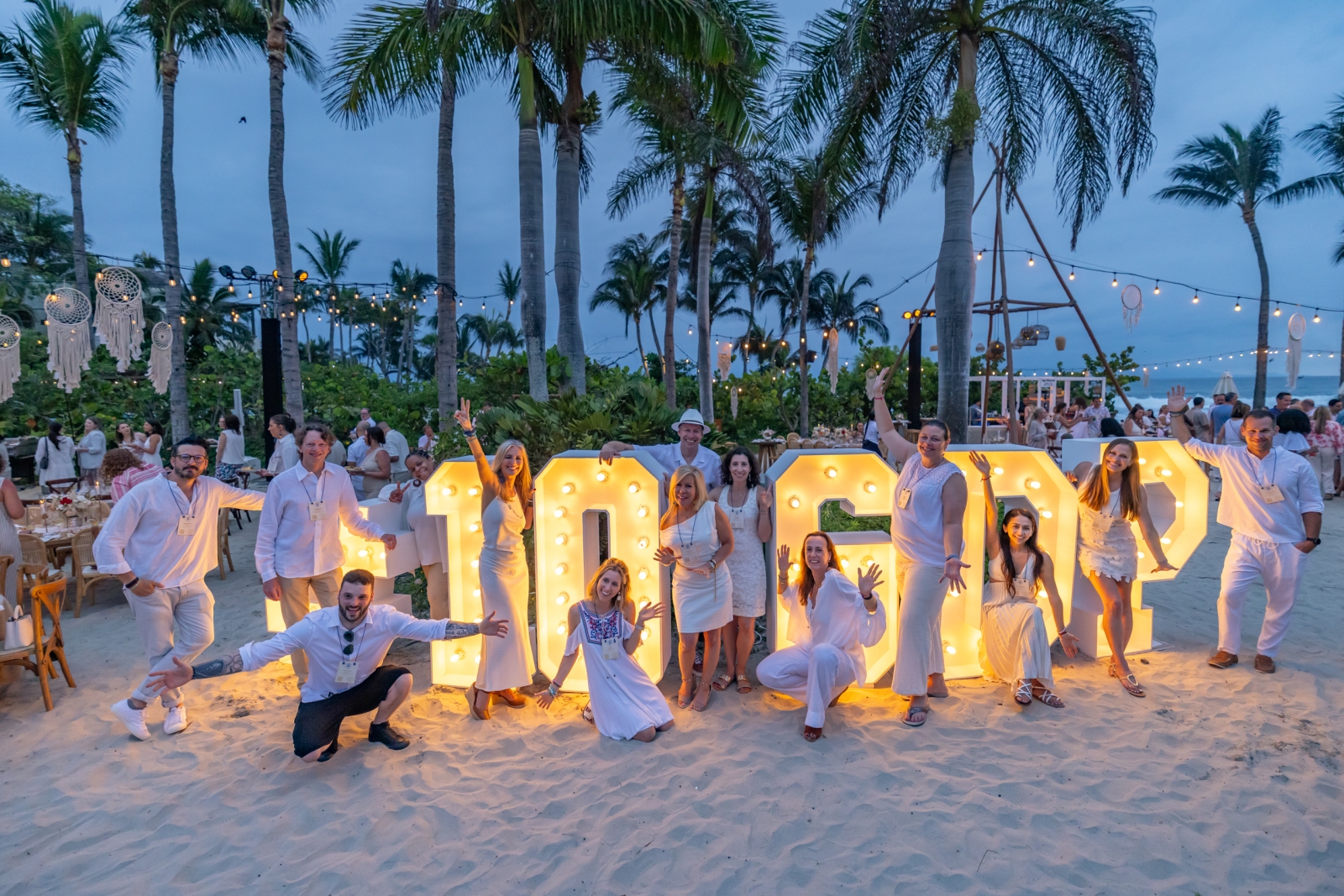 Global DMC team poses in front of #10 GDP sign on the beach